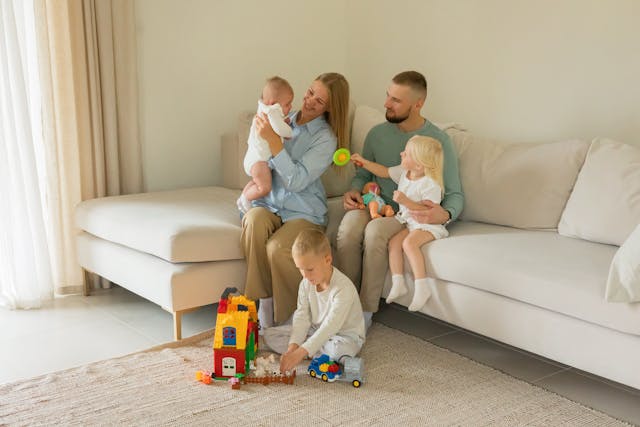 Family sitting on a cocuh and playing with toys while smiling
